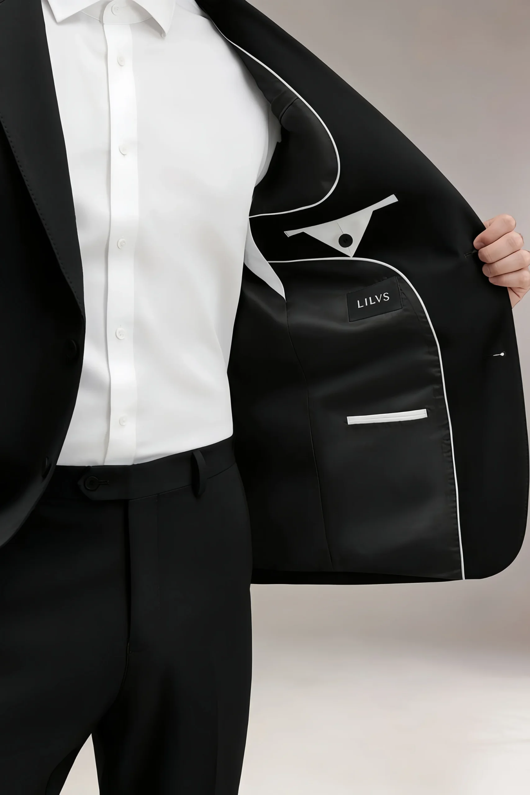 Close-up of LILVS Jago black flat-front tailored trousers showing waistband, straight leg and crease with brown leather shoes